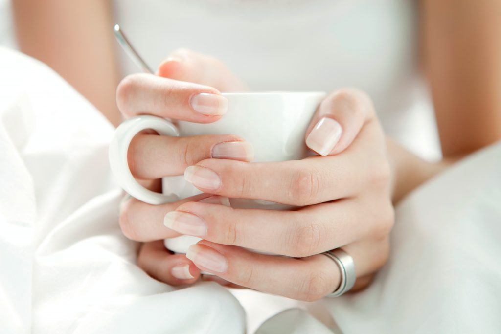 nude nails holding cup of tea